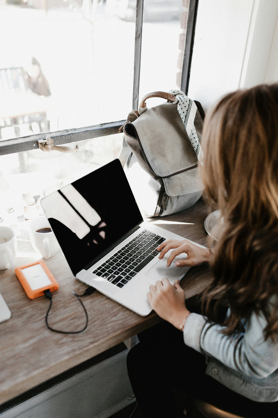 Person using a laptop at a desk with a backpack in the background
